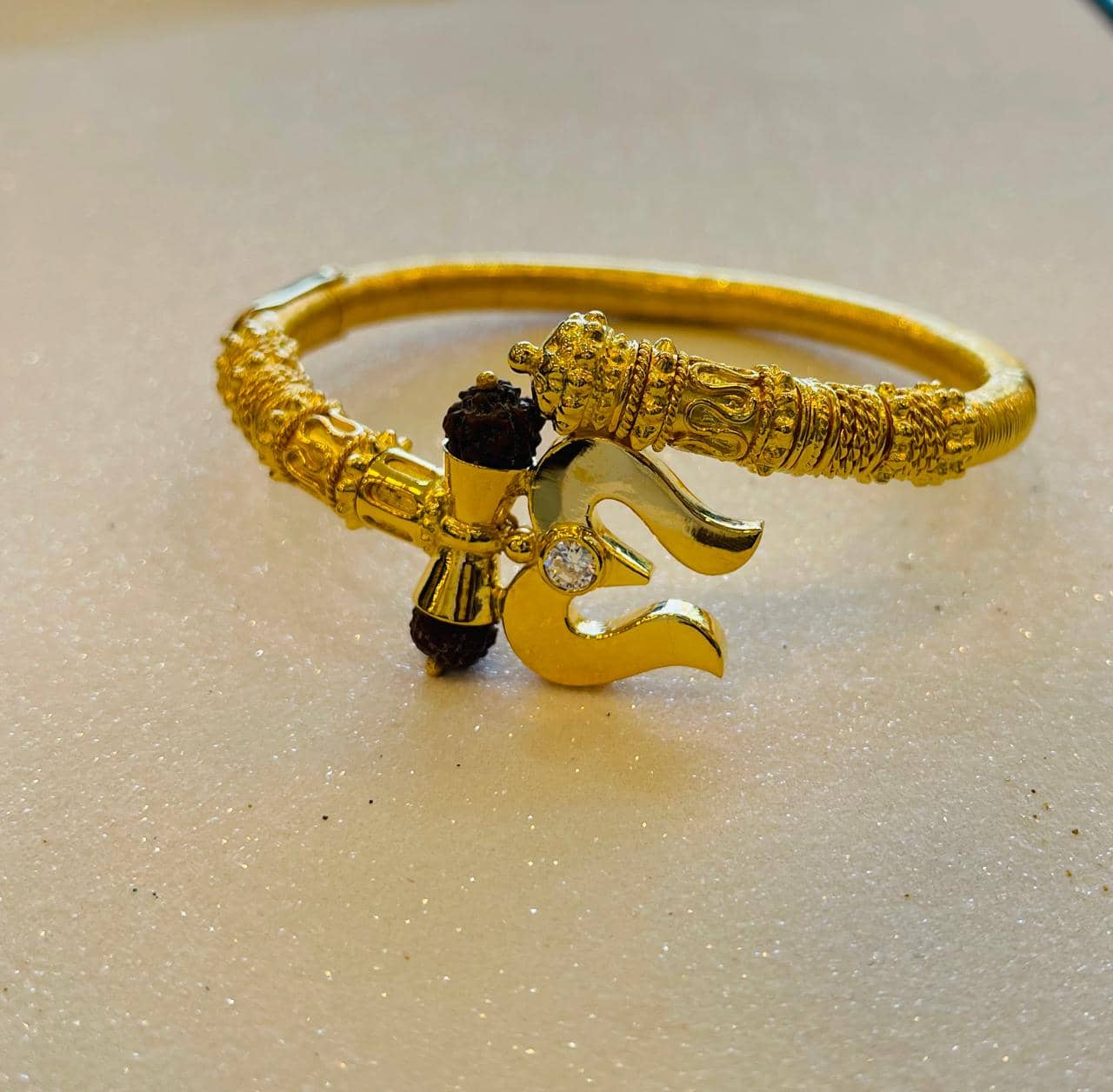 Ornate gold kada bangle with a symbolic centrepiece
