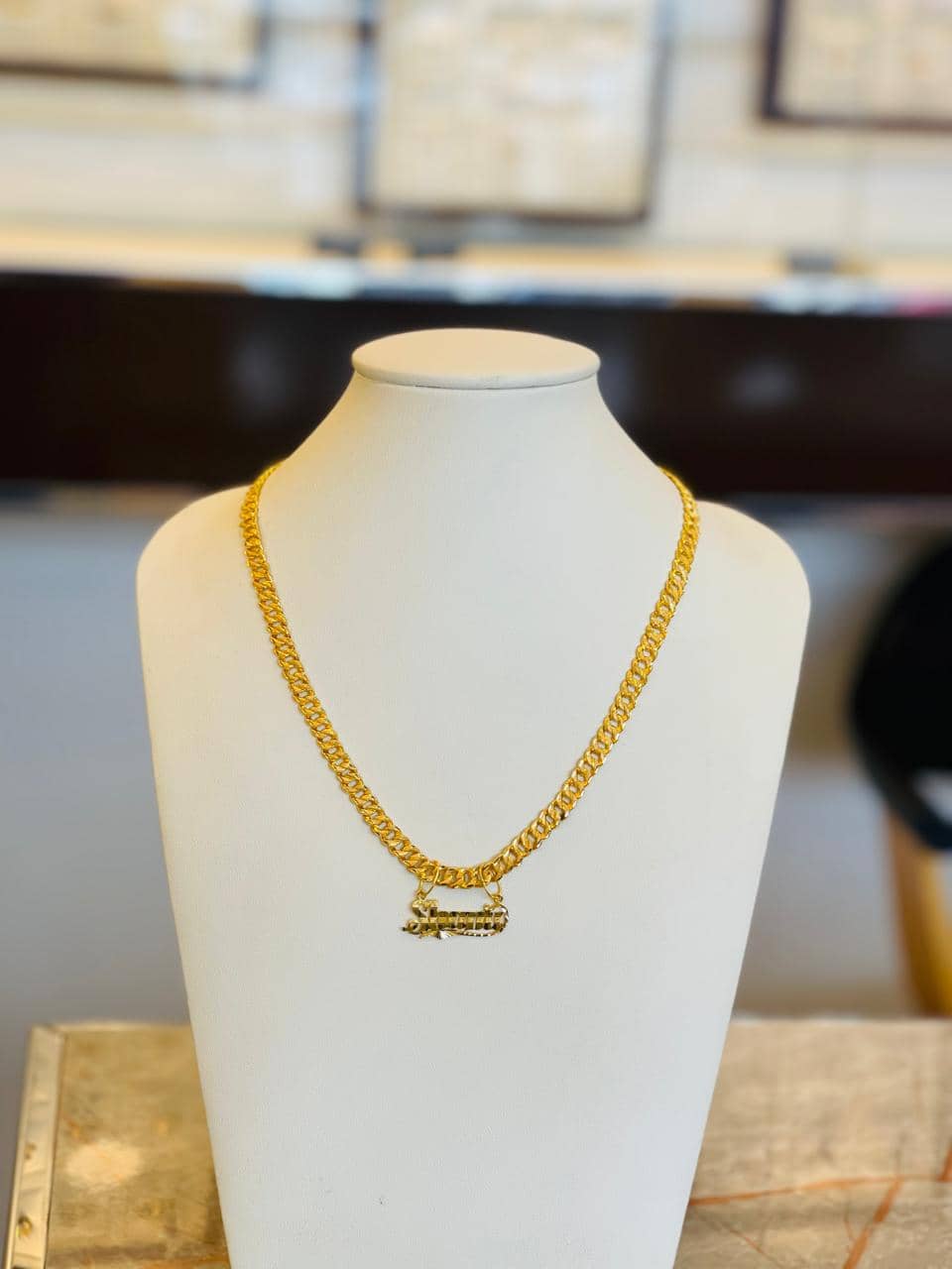 Gold script name necklace on a display bust