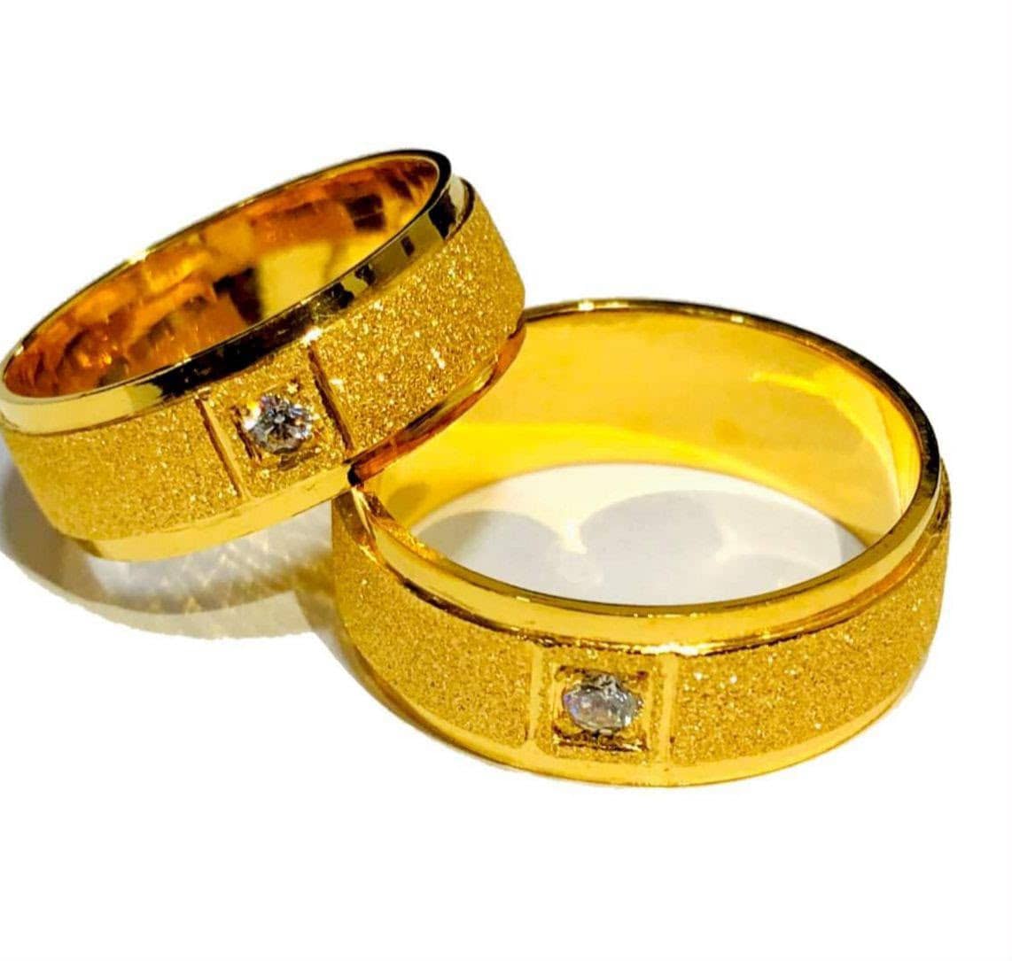 A pair of textured gold wedding bands, each set with a stone