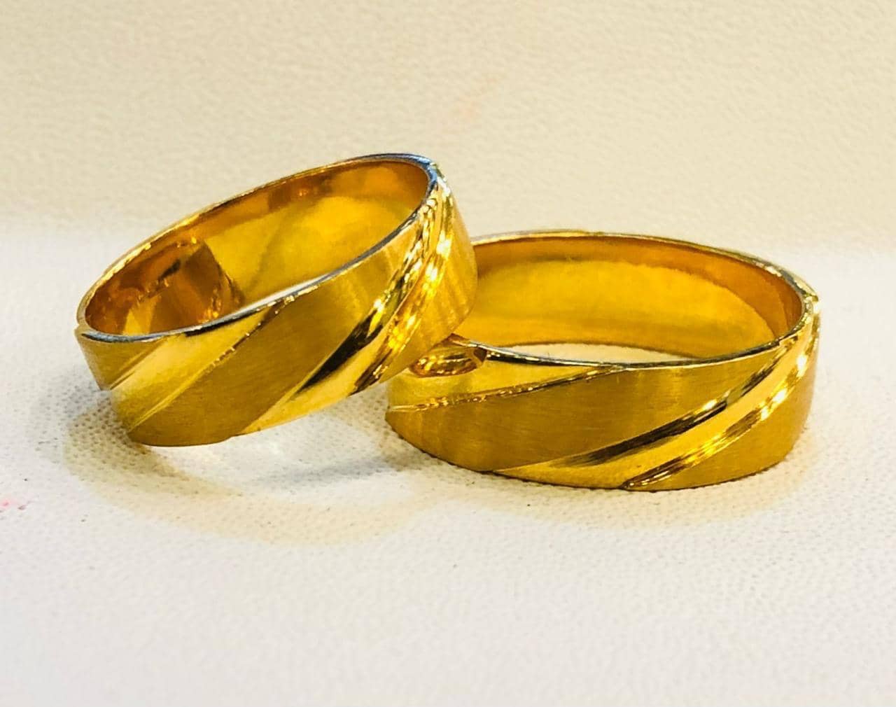 A pair of polished gold wedding bands with diagonal detailing