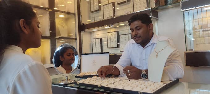 A JK Gold House jeweller presenting necklaces to a customer