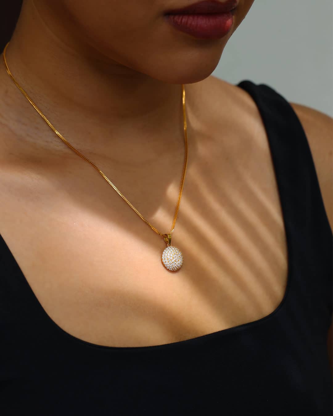 Pavé-set round gold pendant on a fine gold chain