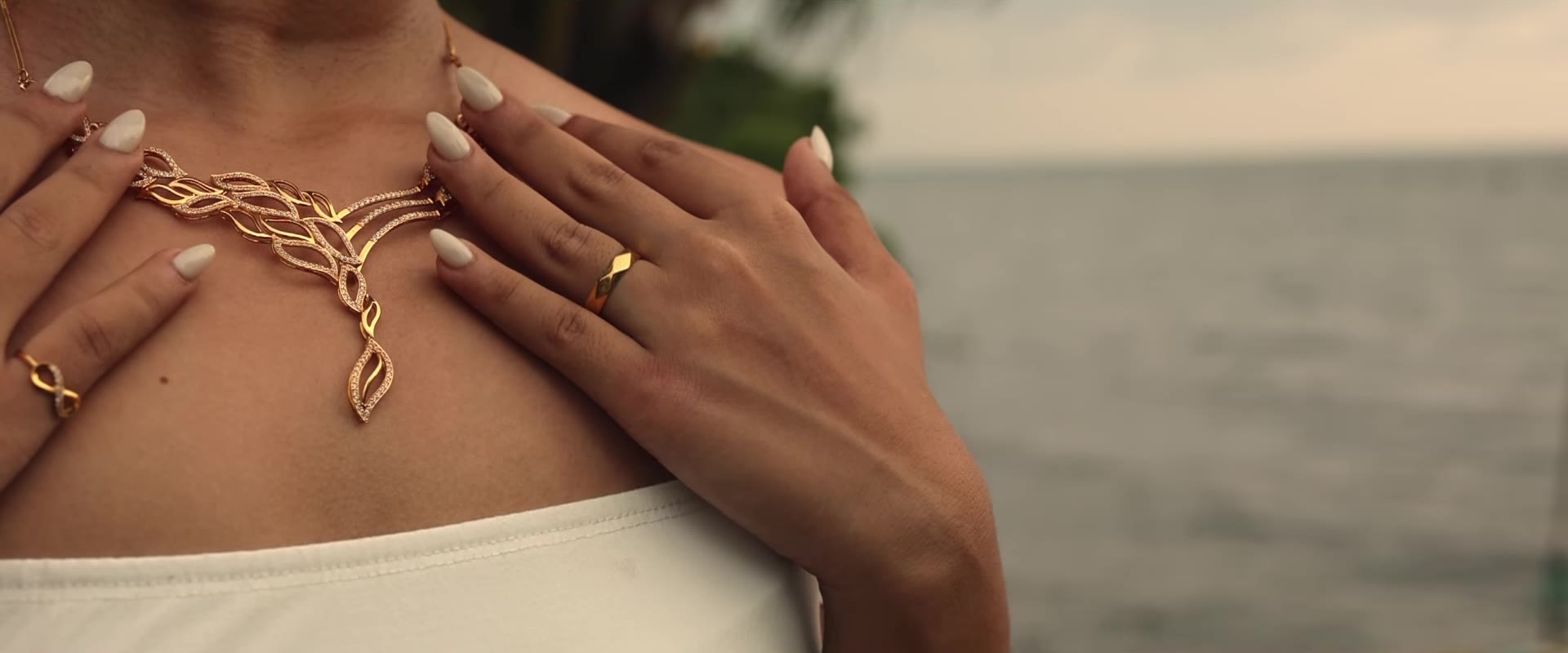 Gold leaf necklace and ring photographed by the sea