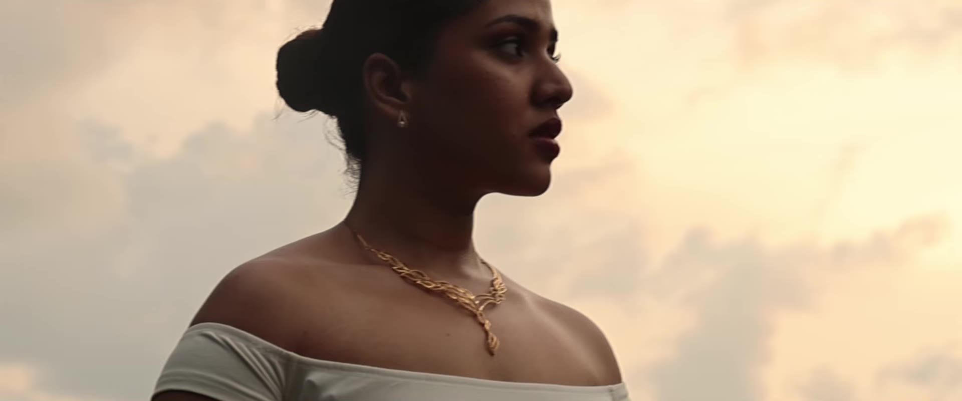 Woman wearing a delicate gold necklace at golden hour